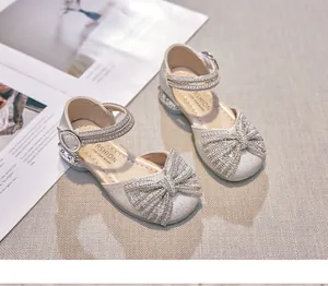 Detail view of silver glittery girls' princess sandals with rhinestone bow and straps