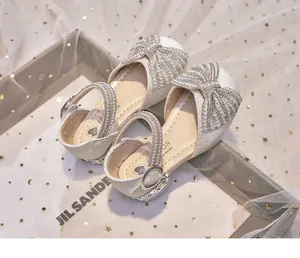 Elegant girl's sparkly princess sandals featuring a rhinestone bow and pearl accents