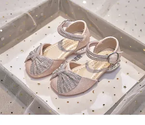 Sparkling pink girls' princess sandals with rhinestone bow and pearl straps detail view.