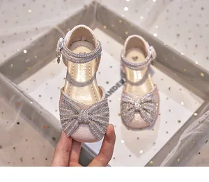 Detail view of pink sparkly girls' sandals with rhinestone bow and pearl strap.