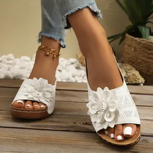 Vista detallada de sandalias de cuña blancas con flor 3D y patrones de corte láser.