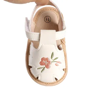 Close-up of white baby girl summer sandal with delicate floral embroidery details