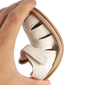 Detail view showing the extreme flexibility of the soft cream baby sandal sole.
