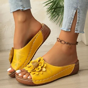 Primer plano de sandalias con cuña amarillas con flor decorativa y costuras blancas