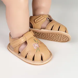 Close-up of tan baby girl sandals with pink flower embroidery and non-slip soft soles.