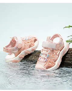 Detail shot of pink kids mesh sports sandals with closed-toe design on water and log.