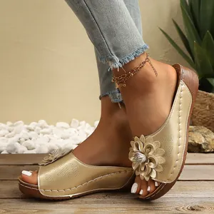 Vista de detalle de sandalias de cuña color champán con elegante adorno floral