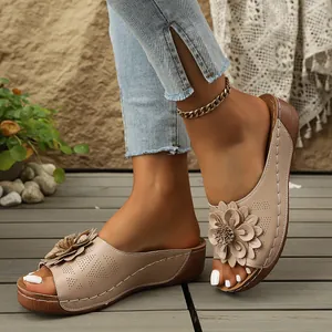 Detalle de sandalias de cuña beige para mujer con flor 3D decorativa y costuras