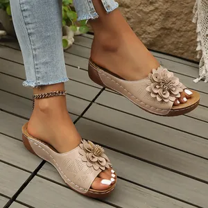Vista detallada de sandalias con cuña beige con elegante adorno floral y tira perforada