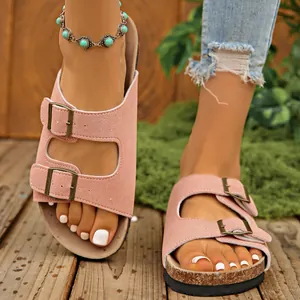 Close-up of stylish pink double buckle sandals on feet featuring cork platform soles