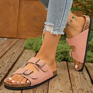 Pink suede-style double buckle slides with cork sole on feet outdoors