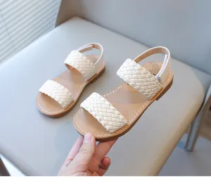 Close-up view of elegant beige children's sandals with stylish braided straps and secure backstraps.