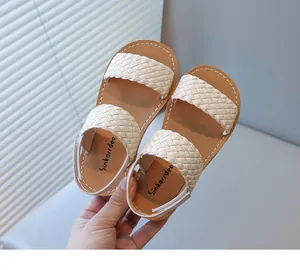 Close-up detail of children's beige woven strap sandals with soft tan footbeds and secure straps
