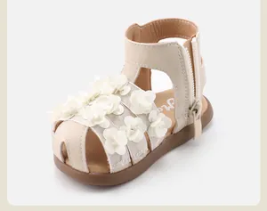 Detailed view of beige toddler sandals with delicate white 3D floral decorations.