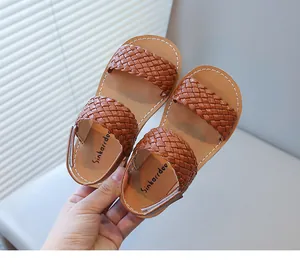 Detail of brown woven toddler girl beach sandals featuring white stitching and velcro