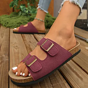 Close-up of burgundy double-strap sandals with gold buckles on cork footbed