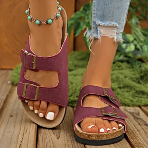 Detail view of burgundy double buckle platform slide sandals for women on a wooden deck