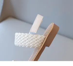 Detail of the woven cream strap and stitched tan sole of girls summer beach sandals
