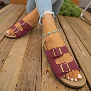 Close-up view of stylish burgundy double-buckle platform sandals on a wooden deck