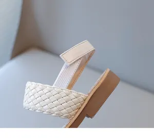 Close-up detail of the woven white strap and adjustable ankle strap of a child's sandal