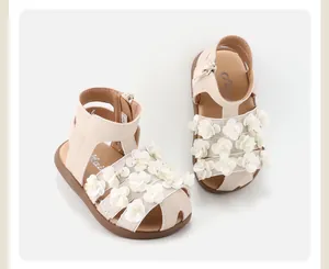 Detailed view of baby girl beige sandals with delicate white flower decorations