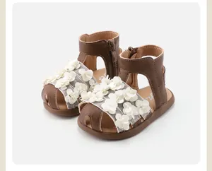 Detailed view of toddler girl's brown sandals with delicate white 3D flower accents