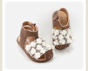 Detailed view of baby girl sandals with 3D white flower appliqués and soft brown leather.