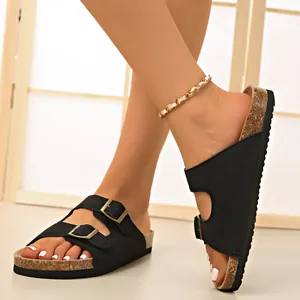 Close-up of black double buckle cork sandals with golden chain anklet detail.