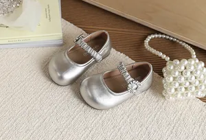 Dettaglio di scarpe Mary Jane argento per bambina con fibbia di strass e finitura metallica.