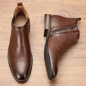 Detail view of men's brown leather Chelsea boots with side zipper on wooden background