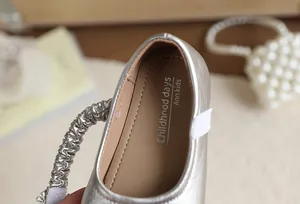 Primo piano di scarpa da principessa argento per bambina con trama metallica.