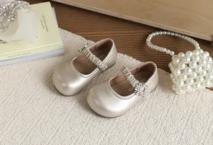 Dettaglio delle scarpe Mary Jane dorate per bambine con fibbia lucida in strass di lusso