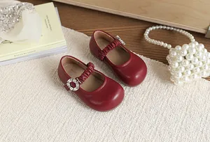 Dettaglio di scarpe Mary Jane in pelle rossa da bambina con fibbia in strass.
