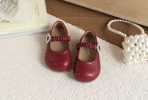 Vista dettagliata di scarpe Mary Jane rosse da bambina con fibbia in strass e perle eleganti.