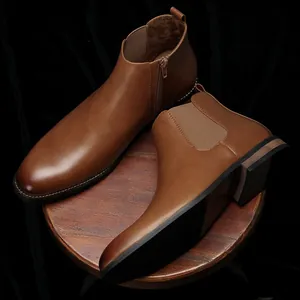 Detailed view of classic brown leather Chelsea boots displayed on a rustic wooden pedestal