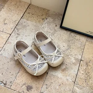 Détail de la dentelle et du nœud sur ces chaussures Mary Jane crème pour fillettes