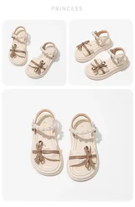Detailed view of cream girls' sandals with decorative bow and pearl strap details.