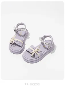 Close-up of lavender girls princess sandals with cream bow and pearl ankle straps.