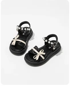 Close-up of black children's princess sandals featuring elegant pearls and white bows.