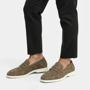 Dettaglio macro di mocassini da uomo in pelle scamosciata taupe con suola bianca in stile slip-on