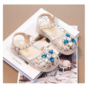 Detailed view of girls' princess sandals with blue crystal flower and pearls.