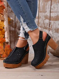 Primo piano di sabot neri con plateau traforato, tacchi grossi e stile retrò chic.