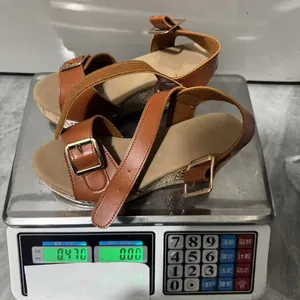 Detail view of brown platform wedge sandals with buckle straps being weighed on a scale