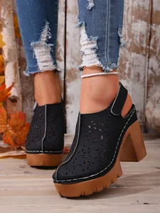 Vista dettagliata dei sabot vintage neri con motivo traforato e suola platform alta