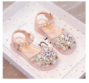 Close-up of pink glitter girls' sandals with crystal flower and pearl ankle strap