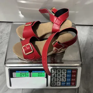 Detail view of red wedge sandals with gold buckles on a scale showing 0.490 kg weight.