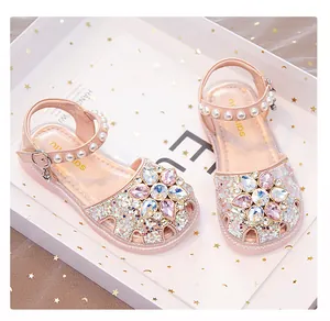Close-up of pink glittery girls' sandals featuring rhinestone flowers and pearl straps