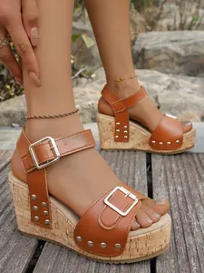 Close-up detail of stylish brown leather wedge sandals with metal rivets and buckle straps
