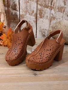 Dettaglio sabot vintage marroni con tacco largo e plateau e motivi traforati per donna