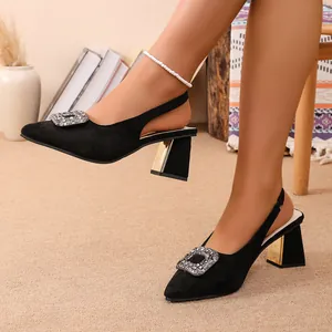 Détail d'escarpins noirs en daim avec boucle élégante en strass et talon bloc doré chic